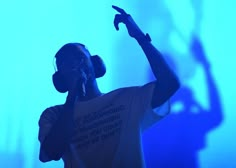 a man with headphones on talking on a cell phone in front of a blue background