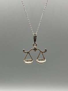 a silver necklace with an image of a balance scale on the front and back sides