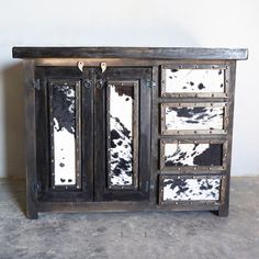 a black and white cabinet sitting on top of a cement floor next to a wall