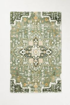 a green rug with an intricate design on the front and back side, in various colors