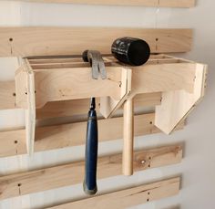 a wooden rack with tools hanging from it's sides and two pegs attached to the wall