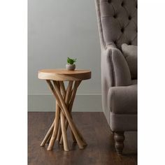 a small wooden table with a plant on it in front of a chair and wall