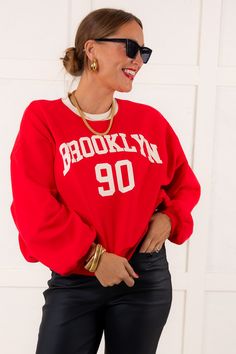 Experience ultimate comfort and style with our Brooklyn Sweatshirt. Made with a fleece interior, this sweatshirt features a rounded neckline, long sleeves, and a Brooklyn graphic on the front. Perfect for any casual occasion. Model is wearing a size Small. Runs true to size 60% Cotton, 40% Polyester Size Small Measurements Bust: 30" Length: 22" Size Large Measurements Bust: 32" Length: 23" Washing Instructions Hand wash cold separately. Do not bleach. Hang to dry. Collegiate Long Sleeve Graphic Hoodie, Varsity Long Sleeve Tops For Campus, Trendy Campus Sweatshirt For Fall, Trendy Sweatshirt For Campus In Fall, Trendy Fall Sweatshirt For Campus, Long Sleeve Tops With Ribbed Cuffs For Campus, Varsity French Terry Sweatshirt For Fall, Fall Varsity Sweatshirt In French Terry, Red Crew Neck Sweatshirt With Ribbed Cuffs