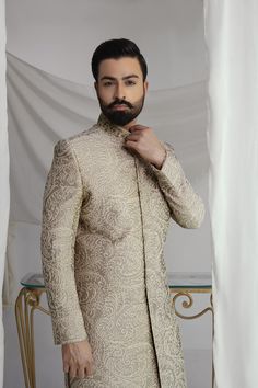 This light brown sherwani features intricate thread jal and a silk inner kurta pajama, paired with a tissue silk Rajasthani kula (turban) and a ruby stone brooch. Elevate your style with this royal look, perfect for special occasions. 4-Piece Suit Elegant Raw Silk Sherwani With Dabka Detailing, Elegant Raw Silk Nehru Jacket With Traditional Drape, Elegant Raw Silk Sherwani With Traditional Drape, Elegant Nehru Jacket In Raw Silk With Traditional Drape, Elegant Raw Silk Bandhgala For Eid, Unstitched Elegant Nehru Jacket For Eid, Elegant Unstitched Nehru Jacket For Eid, Elegant Raw Silk Nehru Jacket For Festive Occasions, Elegant Raw Silk Bandhgala For Festive Occasions