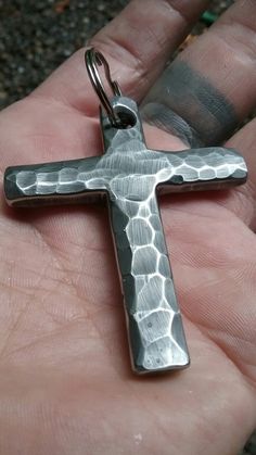 a person is holding a silver cross in their hand