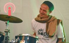 a man is smiling while playing the drums