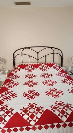 a bed with a red and white quilt on it