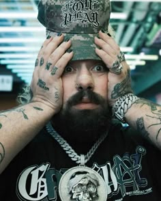 a man with tattoos and a hat covering his face