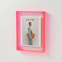 a pink neon frame holds a photo of a man in blue and orange holding a handbag