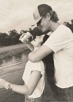 a man and woman standing next to each other near water