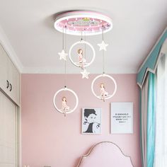 a bedroom with pink walls, white bedding and stars hanging from the ceiling above it