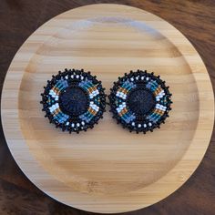 These earrings are made with seed beads and black centers encircled in black rhinestone. They are then branded with our logo, backed with moose hide and your choice of earring findings. The edging is done with black rondelle beads, creating and extra bit of sparkle as the earrings move about. Each pair are made with hypoallergenic materials for sensitive ears. You can now upgrade your earring to include a tassel attachment. This upgrade allows you to have a 3 in 1 pair of earrings. The tassel ea Round Beaded Earrings Native American, Beaded Round Earrings, Beaded Items, Native Beading, Diy Wire Earrings, Stitch Earrings, Native Crafts, Beaded Earrings Native, Earrings Patterns