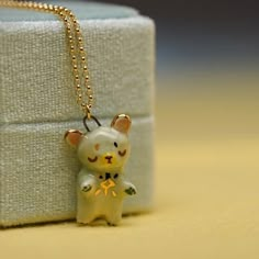 a small toy cat is sitting on a box with a chain around it's neck