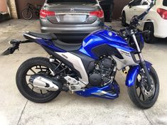 a blue and silver motorcycle parked in front of a car