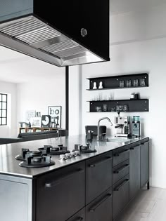 a kitchen with stainless steel counter tops and black cabinets, along with open shelving