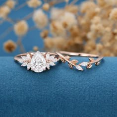 two wedding rings with leaves on them sitting on a blue surface next to dried flowers