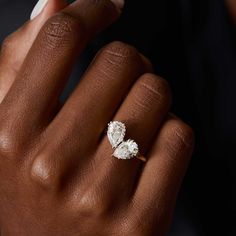 a woman's hand holding an engagement ring with two pear shaped diamonds on it