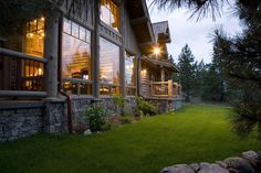 a house that is lit up at night with lights on the windows and grass in front of it