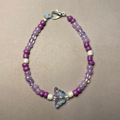 Elevate your ensemble with our Whimsical Butterfly Purple Beaded Bracelet. Handcrafted with care, this charming piece features an assortment of purple beads in various shades, complemented by delicate white pearl-colored beads for an added touch of elegance. At its heart, a delightful butterfly-shaped bead in clear blue and purple tones steals the spotlight, infusing the bracelet with a whimsical allure. Available in two lengths: 18cm and 20cm, this bracelet offers versatility and comfort for everyday wear. Whether worn as a personal statement or gifted to a loved one, our Whimsical Butterfly Purple Beaded Bracelet brings a playful pop of color and style to any outfit. This was also inspired by the K-Pop group BTS and their beautiful song Butterfly Bohemian Purple Bracelets With Heart Beads, Purple Heart Beaded Bracelets, Lavender Bracelets With Colorful Beads, Adjustable Purple Beaded Bracelets With Heart Beads, Purple Tiny Beads Beaded Bracelets As Gift, Purple Beaded Bracelets With Heart Beads For Gifts, Lavender Beaded Bracelets With Tiny Round Beads, Lavender Beaded Bracelets With Spacer Beads, Lavender Beaded Bracelets With Round Spacer Beads