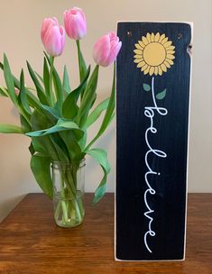 a vase with pink tulips sitting next to a sign that says hope