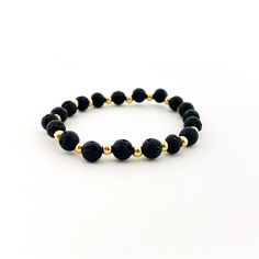 Isabelle Gold Accented Single Pattern Lava Stone Bracelet | 6MM - MTT Collective Elegant Black Lava Stone Beaded Bracelets, Elegant Lava Stone Beaded Bracelets, Elegant Black Lava Stone Jewelry, Adjustable Black Lava Stone Bracelet, Black Hand-strung Lava Stone Beaded Bracelets, Lava Stone Bracelet, Lava Beads, Lava Bead, Lava Stone