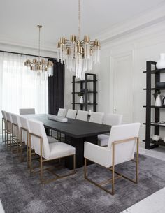 a dining room table with white chairs and gold chandelier hanging from the ceiling