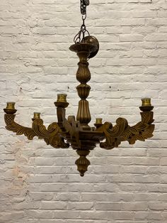 a chandelier hanging from the ceiling in front of a white brick wall,