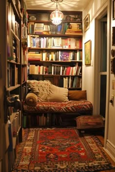 a room filled with lots of books and rugs next to a doorway that leads to another room