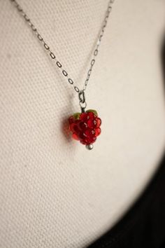 a close up of a necklace on a mannequin's torso with a strawberry