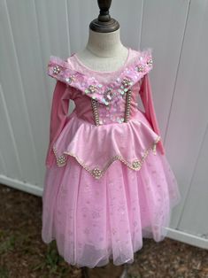 Step into a world of fairy tale magic with our Enchanted Rose Princess Dress. This beautiful pink dress features a shimmering bodice adorned with sparkling sequins, intricate floral embroidery, and delicate jewel accents. The layered tulle skirt, decorated with glittering star patterns, adds a touch of whimsy and elegance. Long sleeves provide extra warmth and comfort, making this dress perfect for cooler days. Ideal for themed parties, dress-up play, or any special occasion, this dress will mak Spring Embellished Princess Dress, Spring Pink Embellished Princess Dress, Princess Pageant Dress With Sequins, Princess Style Sequined Tutu Dress For Dress-up, Princess Style Sequined Dress For Pageant, Princess Ball Gown Dress With Sequins, Princess Style Sequined Dress For Pageants, Princess Style Sequin Dress With Glitter Tulle, Pink Princess Dress With Sequins For Wedding