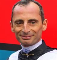 a man wearing a black and white shirt with a cross on his chest smiling at the camera