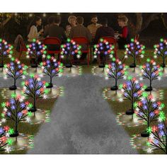 a group of people sitting at a table with christmas lights on trees in the middle