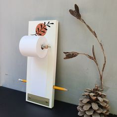 a toilet paper dispenser next to a pine cone