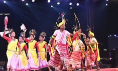 a group of people standing on top of a stage next to each other holding arrows