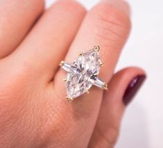 a woman's hand holding an engagement ring with two pear shaped diamonds