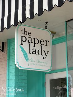 the paper lady sign is hanging from the building's awning above it are several cupcakes