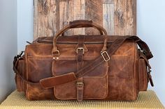 "Genuine Leather Travel Duffel Bag. PURE LEATHER: Bags are made of full grain genuine leather. Vintage inspired design combined with the distressed leather gives a rich classy look. Inside of the bag is lined. One zippered pocket inside of the bag, three pockets outside of the bag. SIZE: 22''x 11.5'' x 11\" Open Pockets within the front pocket can be a great place for your belongings like mobile phone, wallet, headphones. Use it for a mini vacation, gym or for just running around town; this leat Leather Weekender Bag In Cognac For Overnight Trips, Leather Cognac Weekender Bag For Overnight Trips, Rugged Leather Duffle Bag For Travel, Travel Bags With Oiled Leather And Leather Backing, Travel Bags In Oiled Leather With Leather Backing, Leather Satchel Duffle Bag For Trips, Brown Leather Satchel With Luggage Sleeve, Leather Cognac Satchel With Luggage Sleeve, Rugged Leather Rectangular Duffle Bag