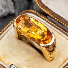 This exquisite cocktail ring is centered with one (1) oval mixed cut natural citrine set into a semi-bezel. The shank is accented with fourteen (14), flush set, round mixed cut natural yellow sapphires. The ring measures 10.0mm at the top, rises 8.3mm above the finger, tapering to 3.7mm wide and 1.4mm thick at the base of the shank. This ring is currently a size 7. Yellow Topaz Ring With Round Cut For Formal Occasions, Oval Amber Topaz Ring For Formal Occasions, Formal Yellow Topaz Ring With Round Cut, Formal Yellow Topaz Ring Round Cut, Formal Yellow Sapphire Ring With Accent Stones, Formal Yellow Oval Topaz Ring, Yellow Sapphire Gemstone Ring For Formal Occasions, Formal Yellow Gold Topaz Ring With Ethical Gemstones, Formal Oval Amber Topaz Ring