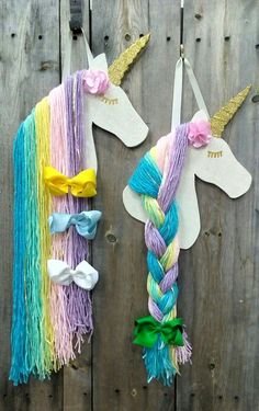 two unicorns made out of yarn are hanging on a fence with hair clips attached to them