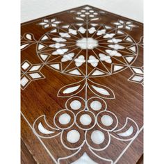 an intricately designed wooden cutting board with white flowers on it