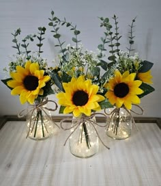 three vases with sunflowers and baby's breath in them