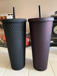 two starbucks cups sitting next to each other on a counter