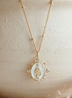 Deepen the faith with the Lady Lourdes Pendant Necklace. Features a white pendant, highlighting a portrait of the Virgin Mary surrounded by ornamental CZ accents and embellished spike details.  Cubic Zirconia 14K Gold Filled White Pendant Jewelry With Miraculous Medal, White Miraculous Medal Pendant Jewelry, Elegant White Miraculous Medal Jewelry, White Miraculous Medal Spiritual Jewelry, Mary Necklace, Virgin Mary Necklace, Our Lady Of Lourdes, Catholic Jewelry, The Virgin Mary