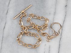 This vintage curb link watch chain is in beautiful condition! Although originally intended to hang from a waistcoat, this chain is a great length for wearing as a necklace. You could even add charms if you so wished! Metal: 14K Yellow Gold Width of Chain: 6.5 mm Length of Chain: 15 Inches Marks: "14" Stamped on the clasp Antique Gold Jewelry With Curb Chain, Antique Gold Necklace With Curb Chain, Antique Gold Curb Chain Necklace, Vintage Brass Chain Necklace With Charm, Vintage Gold Watch, Vintage Brass Tarnish-resistant Chain Necklace, Pocket Watch Chain, Watch Chain, Pocket Watches