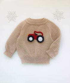 a knitted sweater with a tractor on the front and snowflakes in the back