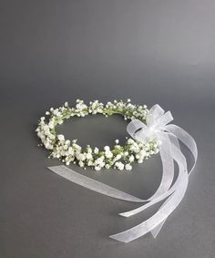 a white headband with baby's breath flowers and ribbons on it, sitting on a gray surface