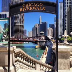 the chicago riverwalk sign is in front of some tall buildings and a body of water