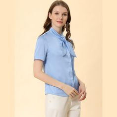 This shirt looks applicable to everyday work clothes in addition to dress-up. The silky fabric shapes this shirt with a tie-neck collared neckline and short sleeves. The curved hem gives it a neat finish over pants. The tie-neck adds casual-inspired sophistication, while soft fabric gives it an elegant, feminine shape. This elegant satin shirt features a tie-bow neck and short sleeves, making it a versatile addition to your wardrobe. Suitable for various occasions including work, office, formal Light Blue Button-up Blouse For Work, Light Blue Collared Shirt For Work, Light Blue Collared Shirt For Office, Blue Collared Blouse For Work, Light Blue Workwear Shirt With Placket, Light Blue Short Sleeve Office Blouse, Workwear Short Sleeve Shirt With Lapel Collar, Blue Office Lady Blouse For Workwear, Light Blue Short Sleeve Blouse With Button Closure