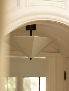 a light fixture hanging from the ceiling in a room with white walls and doorways