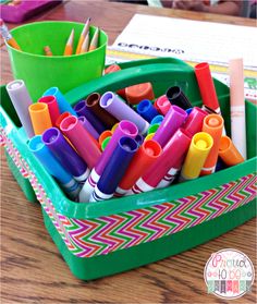 a green container filled with lots of markers and pencils on top of a wooden table